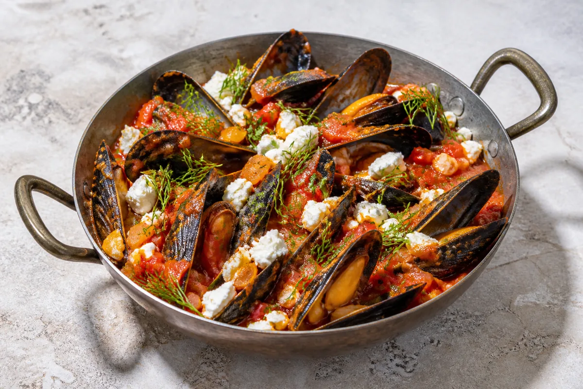 Les moules saganaki finies avec sauce tomate, feta et herbes fraîches